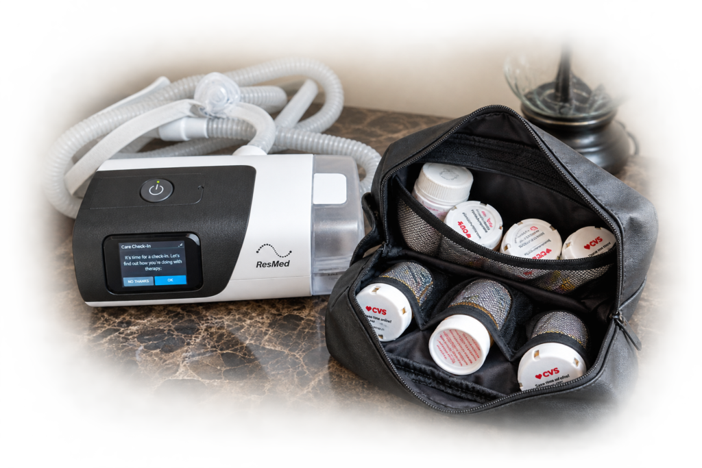Open black medication bag filled with prescription bottles beside a ResMed CPAP machine on a bedside nightstand